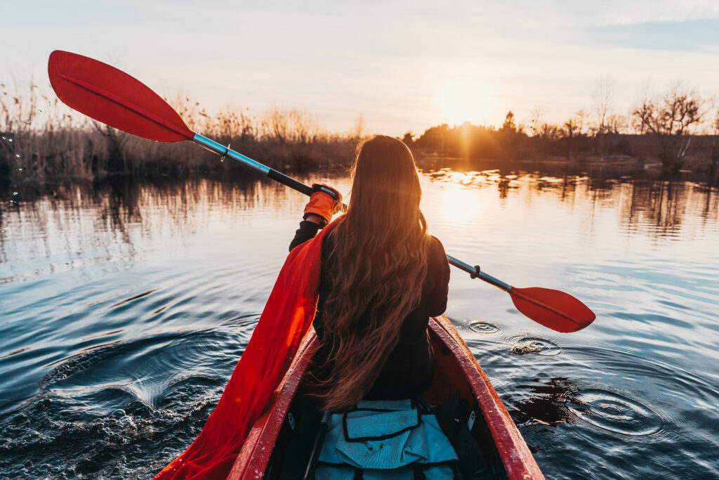 Mujer en un kayak remando sobre aguas tranquilas.